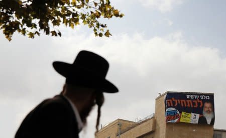 A campaign poster depicting ultra-Orthodox Jewish candidate in Jerusalem's mayoral election Yossi Daitsh is seen on a building as an ultra-Orthodox man looks on, in Jerusalem October 18, 2018. REUTERS/Ammar Awad