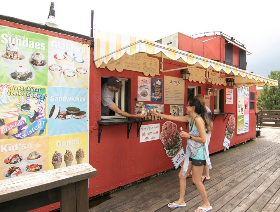 Whistle Stop Ice Cream shop owner Vincent Mileto hands soft-serve ice cream to April Harrington at the Genoa Township store Thursday, July 8, 2021.