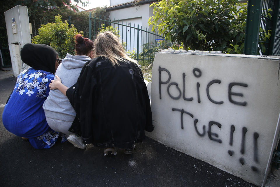 FILE - In this July 5, 2018 file photo, girls lay flowers at the site where police shot of a driver apparently trying to avoid an identity check earlier that week, and where a graffiti read Police Kills, in Nantes, western France. As videos helped reveal many cases of police brutality, French civil rights activists voiced fears that a new security law would threaten efforts by people from minorities and poor neighborhoods to document incidents involving law enforcement officers. French President Emmanuel Macron's government is pushing a new security bill that would notably make it illegal to publish images of officers with intent to cause them harm (AP Photo/Michel Euler, File)