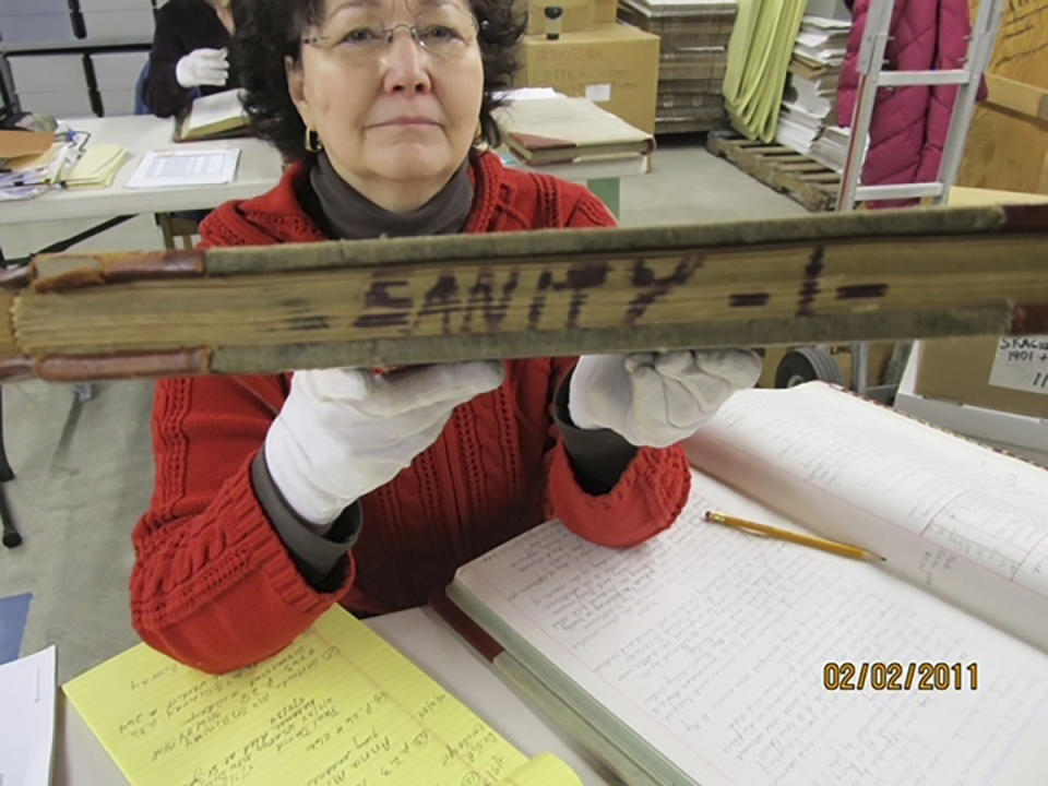 This Feb. 2, 2011, photo shows Niejse Steinkruger at the Alaska state archives in Juneau, Alaska, displaying a book of old court records that included sanity hearings. Steinkruger and other volunteers have spent years digging through old records to identify about 5,500 Alaskans who were committed to a mental hospital in Oregon before Alaska gained statehood. (Roger Brunner via AP)