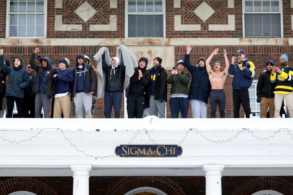 Members of the Sigma Chi fraternity on South State Street join with others yelling and celebrating as the Michigan football team and newly crowned National Champions come past them in pickup trucks and old fire trucks during the parade on campus in Ann Arbor on Saturday, January 13, 2024.