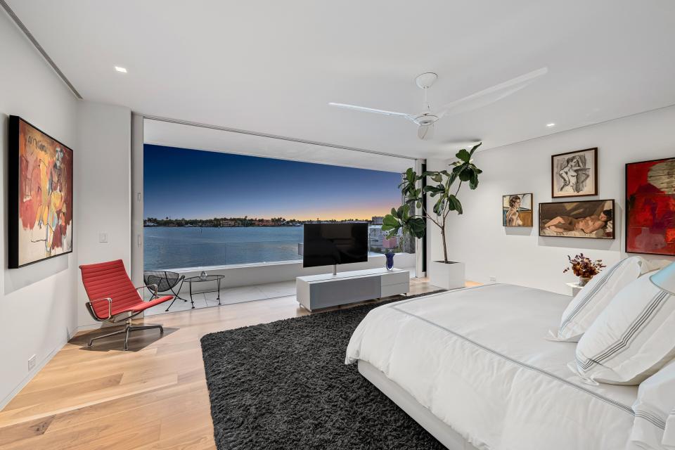 The master bedroom has a wall of windows overlooking Naples Bay. The nearby master bathroom features both an indoor and outdoor shower and glass doors leading to a terrace and cactus garden.