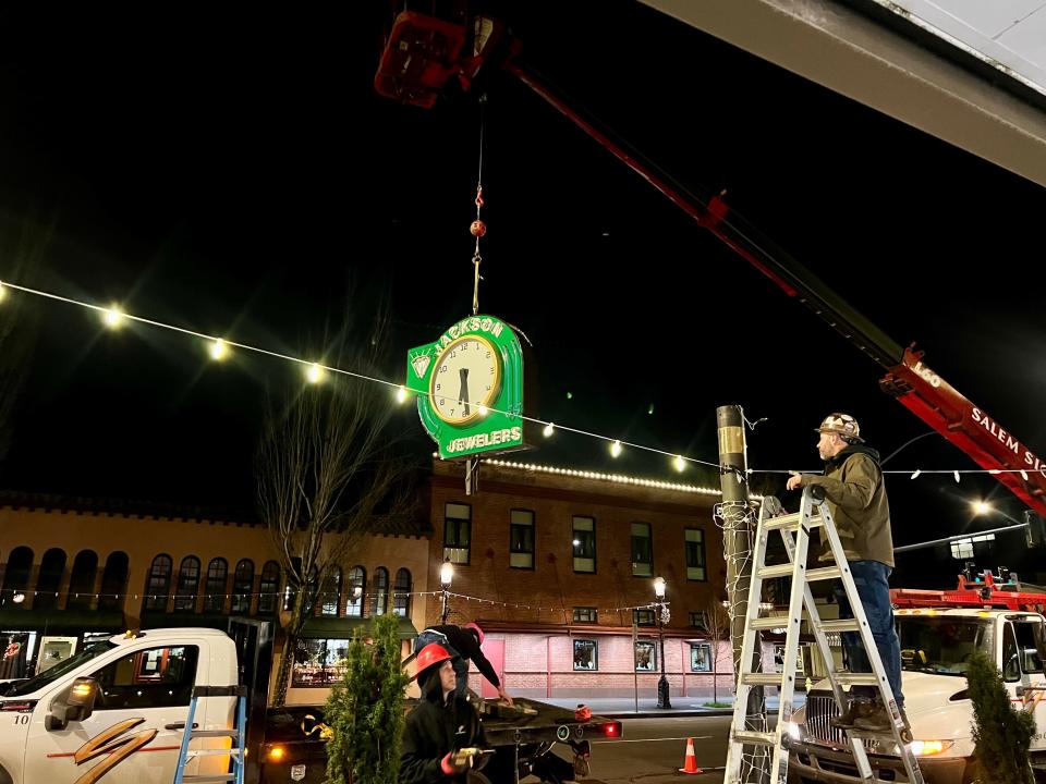 A refurbished Jackson Jewelers clock is remounted Wednesday, Dec. 27, 2023, by Salem Sign Co. on its sidewalk post in downtown Salem, Ore. The street clock has been a fixture of downtown since 1945.