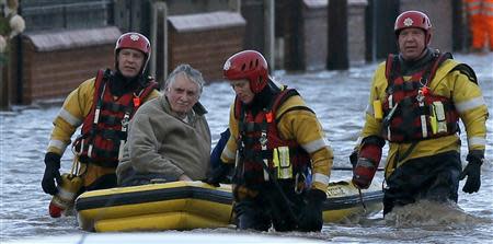 Emergency rescue service workers evacuate a resident in an inflatable boat in flood water in a residential street in Rhyl, north Wales December 5, 2013. REUTERS/Phil Noble