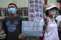 Demonstrators holding a placard that reads "Recover Hong Kong, an era's revolution" stage a protest outside the Queen Elizabeth Stadium in Hong Kong, Thursday, Sept. 26, 2019. Riot police on Thursday begun securing a stadium in downtown Hong Kong ahead of a town hall session by embattled city leader Carrie Lam, aimed at cooling down months of protests for greater democracy in the semi-autonomous Chinese territory. (AP Photo/Vincent Thian)