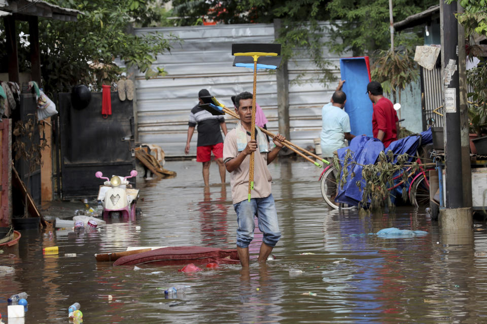 Men prepare to clean their flooded neighborhood in Tanggerang outside Jakarta, Indonesia, Friday, Jan. 3, 2020. Severe flooding in greater Jakarta has killed scores of people and displaced tens of thousands others, the country's disaster management agency said. (AP Photo/Tatan Syuflana)