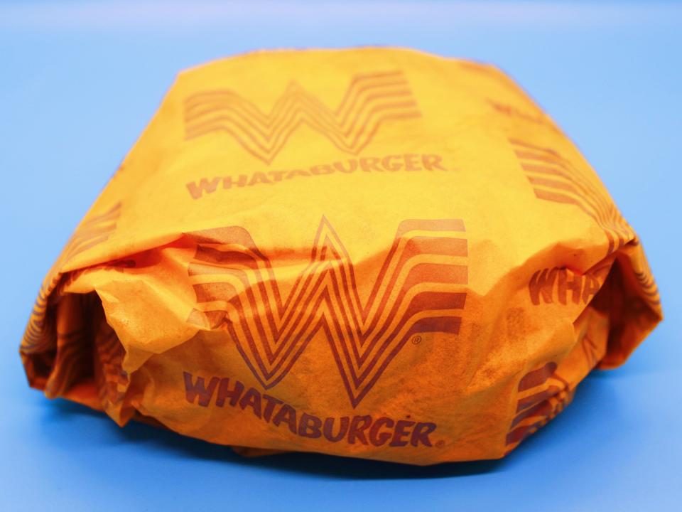 whataburger double cheeseburger in paper packaging on blue background