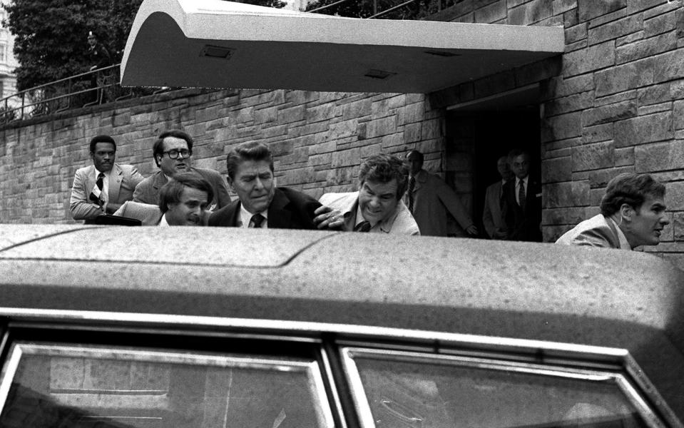 Ronald Reagan is shoved into a car by security following the attempt on his life in 1981