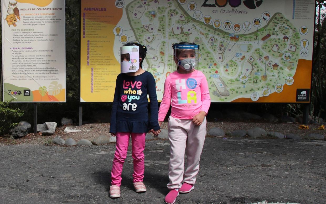 Girls wearing face shields as a preventive measure against the new coronavirus, stand hand in hand as they wait for their parents to enter the zoo on the outskirts of Quito, in Guayllabamba, Ecuador - AP