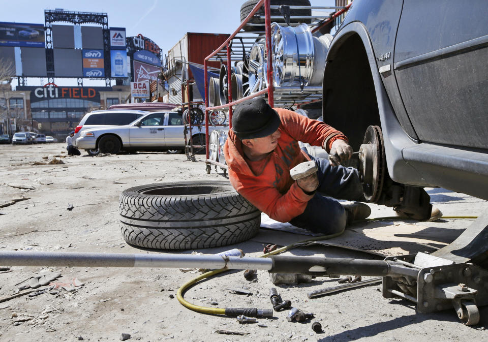 FILE - In this April 2, 2015 photo, Jorge works on repairing a car adjacent to CitiField, home to the New York Mets baseball team in the Willets Point section of the Queens borough of New York. New York City officials approved a plan Thursday, April 11, 2024, to build a 25,000-seat stadium for Major League Soccer’s New York City Football Club next to the New York Mets’ stadium, Citi Field. The $780 million soccer stadium, expected to open in 2027, will anchor a 23-acre redevelopment project in the neighborhood known as Willets Point that will also include housing, a new public school, retail stores and a hotel. (AP Photo/Kathy Willens, File)