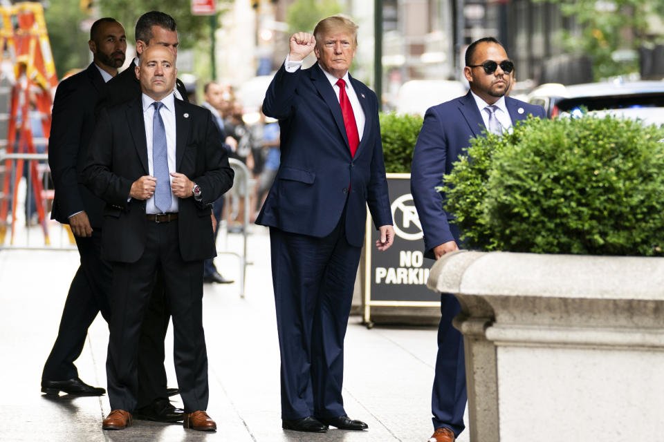 Donald Trump raises his hand in a fist under the awning in front of Trump Tower as he waits for his ride.