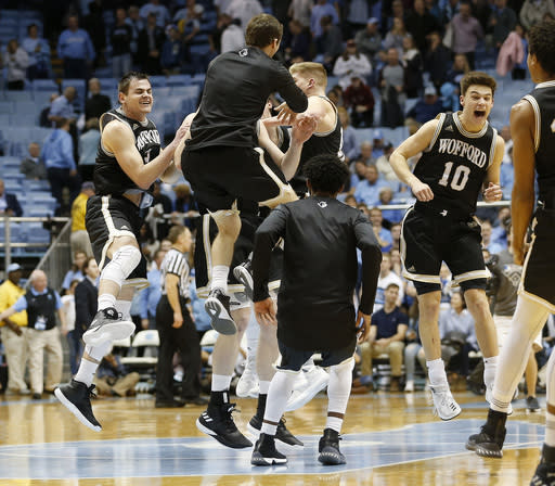 Wofford players including Fletcher Magee, far left, and Nathan Hoover (10) celebrate after beating North Carolina 79-75 an NCAA college basketball game in Chapel Hill, N.C., Wednesday, Dec. 20, 2017. (AP Photo/Ellen Ozier)