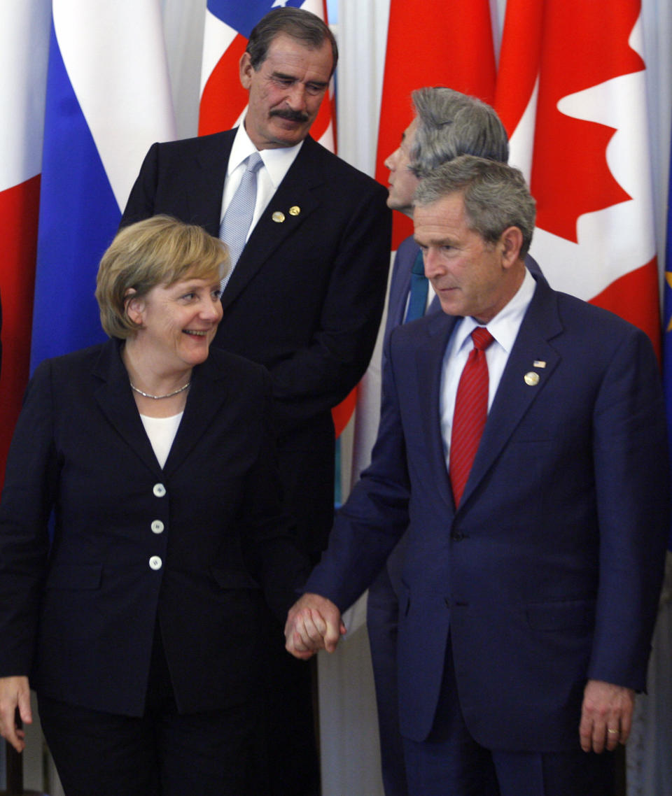 FILE - In this July 17, 2006 file photo, US President George W. Bush holds the hand of German Chancellor Angela Merkel during a group photo at the G8 Summit in St. Petersburg, Russia. Angela Merkel has just about seen it all when it comes to U.S. presidents. Merkel on Thursday makes her first visit to the White House since Joe Biden took office. He is the fourth American president of her nearly 16-year tenure as German chancellor. (AP Photo/Ivan Sekretarev, File)