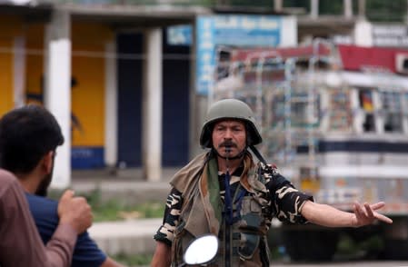 An Indian security force personnel stops people on a motorbike during restrictions after Indian government scrapped special status for Kashmir, in Srinagar