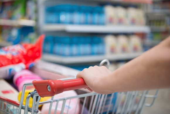 A full grocery cart being pushed through the aisles.