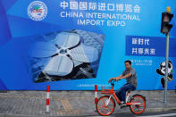 A man rides a bicycle near a billboard promoting the upcoming China International Import Expo in Shanghai, China September 27, 2018. REUTERS/Aly Song - RC1EF430AB50