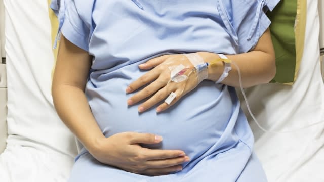 Pregnant woman patient receiving an IV in a bed at a hospital.