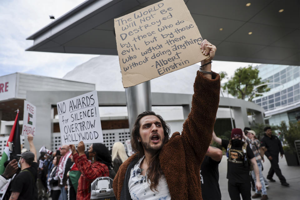 Protesters hold posters during a demonstration in support of Palestinians calling for a ceasefire in Gaza as the 96th Academy Awards Oscars ceremony is held nearby, Sunday, March 10, 2024, in the Hollywood section of Los Angeles. (AP Photo/Etienne Laurent)