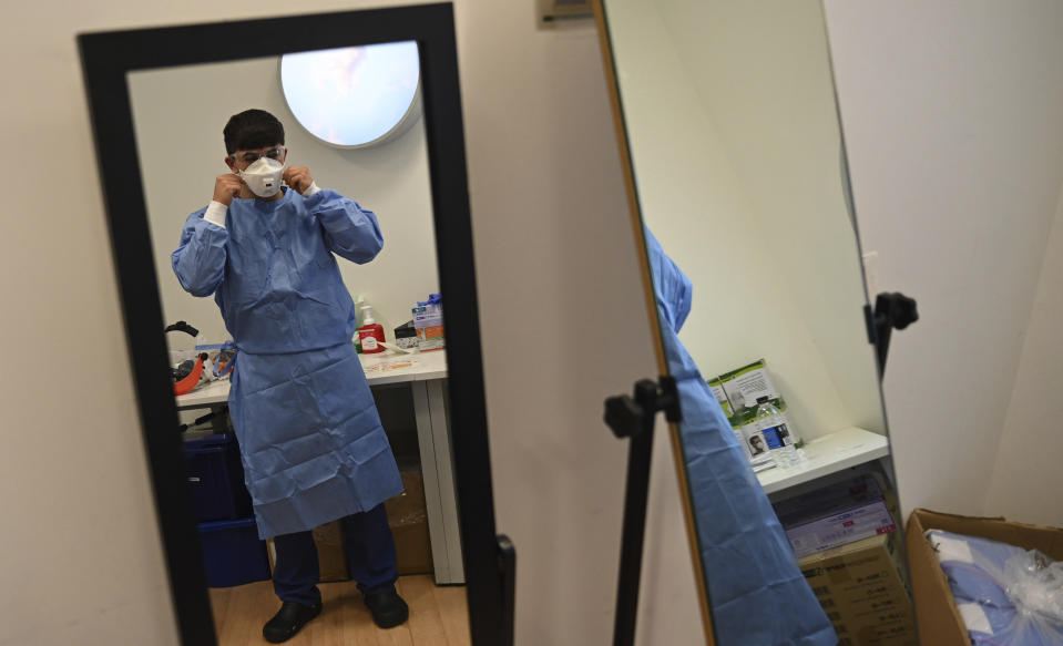 A member of the clinical staff puts on Personal Protective Equipment PPE in the intensive care unit at the Royal Papworth Hospital in Cambridge, England, Tuesday May 5, 2020. (Neil Hall/Pool via AP)