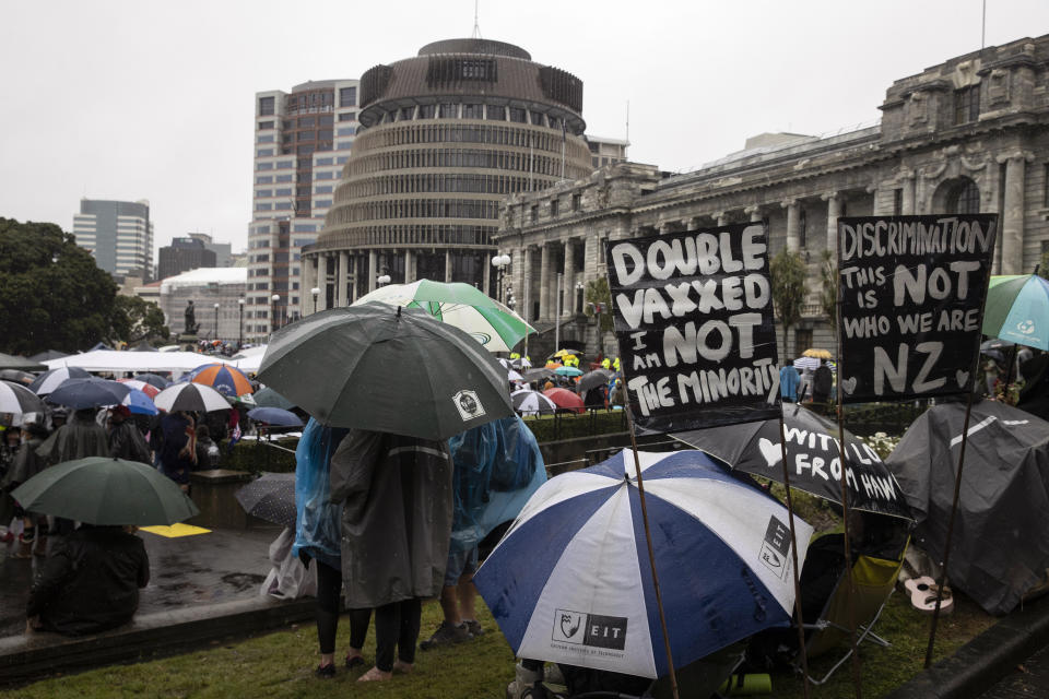 Protesters gather in wet conditions as they voice their opposition to coronavirus vaccine mandates at Parliament in Wellington, New Zealand, Saturday, Feb. 12, 2022. The protest began when a convoy of trucks and cars drove to Parliament from around the nation, inspired by protests in Canada. (George Heard/NZME via AP)