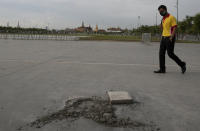 A man walks near a hole at the Sanam Luang field in Bangkok, Thailand, Monday, Sept. 21, 2020. A plaque symbolizing Thailand's transition to democracy has been removed less than 24 hours after it was installed by anti-government demonstrators in a historic royal field. (AP Photo/Sakchai Lalit)