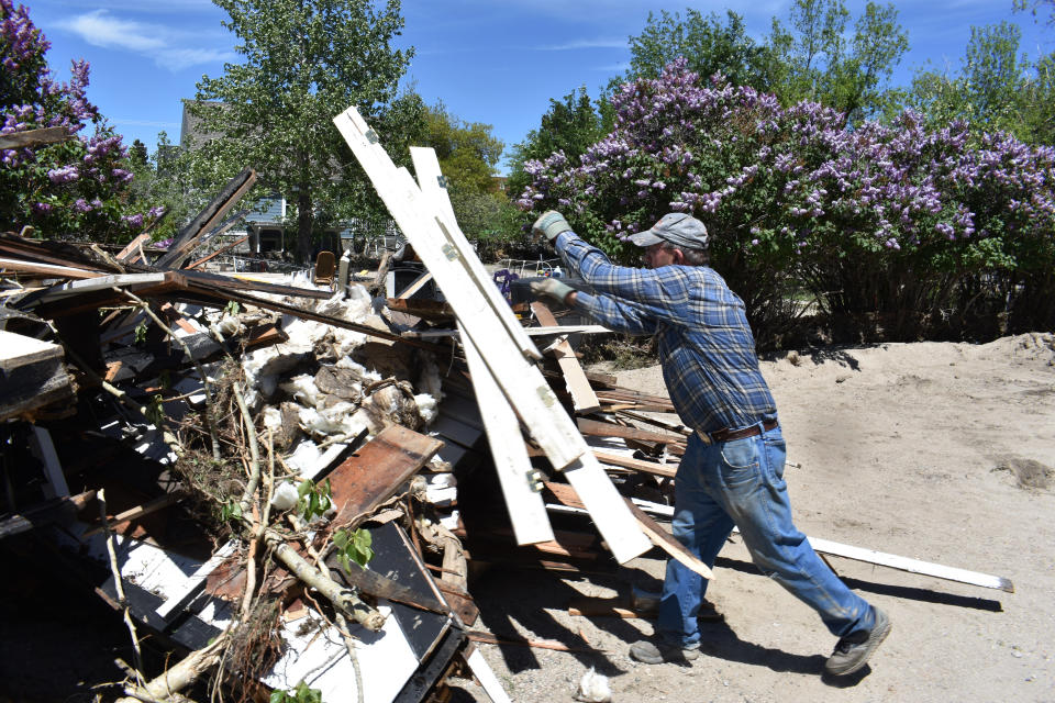 Bob Conover is seen tossing ruined construction materials onto a pile of flood debris in a neighborhood of Red Lodge, Mont., on Thursday, June 16, 2022. Homeowners and business cleaned up from record flooding earlier this week that caused damage to hundreds of homes across southern Montana and forced the indefinite closure of Yellowstone National Park. (AP Photo/Matthew Brown)