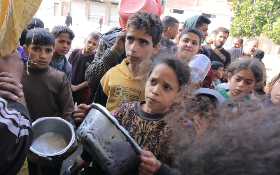 Displaced Palestinian children collect free food from a volunteer-run hospice near Nasser Medical Hospital in Khan Younis, southern Gaza