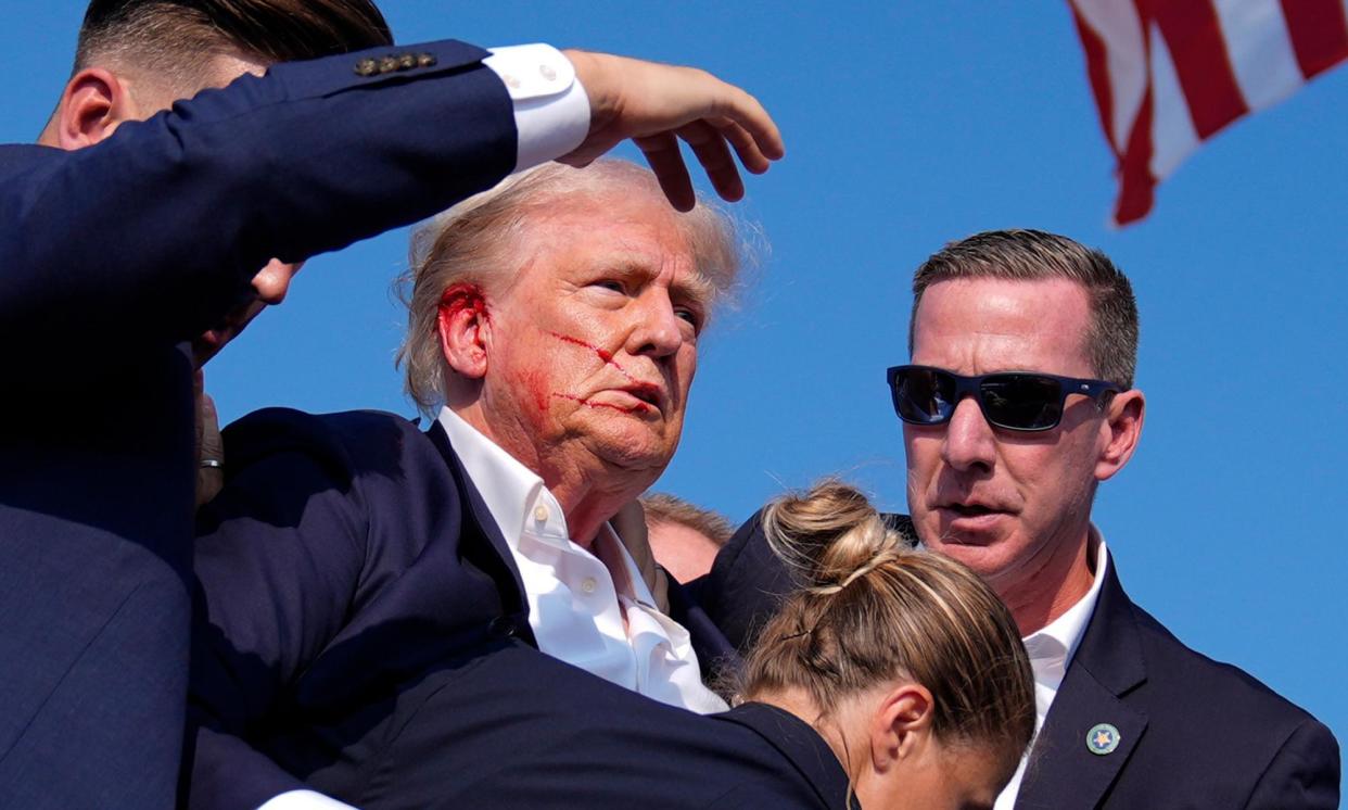 <span>Donald Trump is surrounded by Secret Service agents as he leaves the stage at a campaign rally, in Butler, Pennsylvania, on 13 July.</span><span>Photograph: Evan Vucci/AP</span>