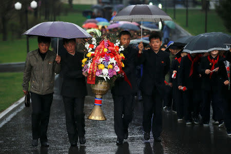 People carry flowers as they arrive to pay respects at the statues of North Korea founder Kim Il Sung and late leader Kim Jong Il in Pyongyang, North Korea April 14, 2017. REUTERS/Damir Sagolj