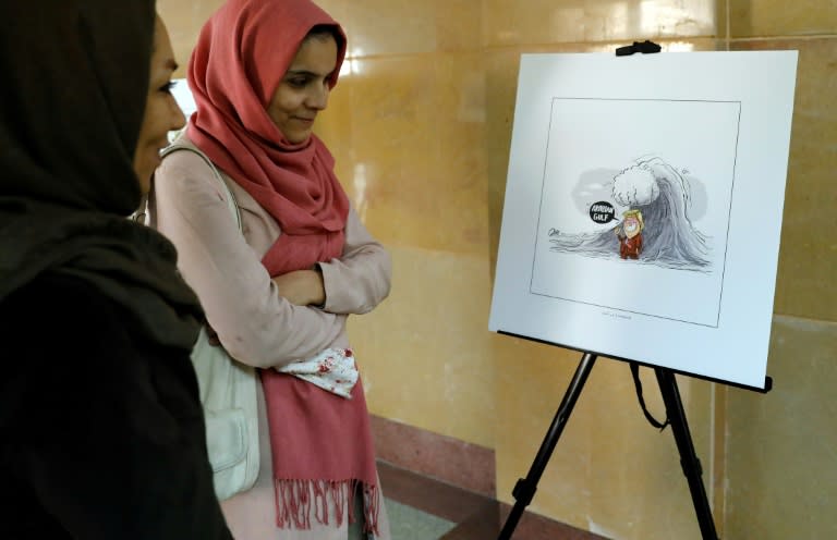 Iranians look at illustrations during the "Persian Gulf Forever" cartoon exhibition in Tehran on October 18, 2017