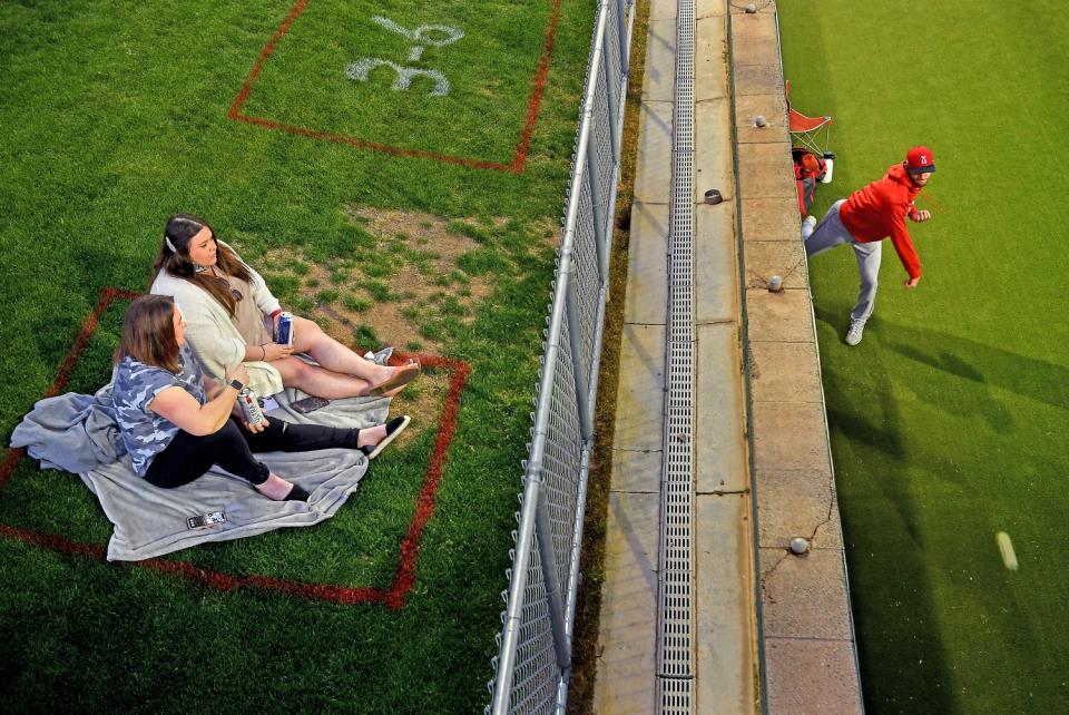 Fans watch from the outfield as an Angels pitcher warms up in the bullpen