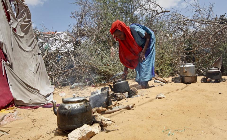 In this photo taken Saturday, Feb. 18, 2017, a displaced Somali girl who fled the drought in southern Somalia cooks on a wood fire in a camp in the capital Mogadishu, Somalia. Thousands of desperate people are streaming into Somalia's capital seeking food as a result a prolonged drought, overwhelming local and international aid agencies, while the Somali government warns of a looming famine, compounded by the country's ongoing conflict against Islamic extremists. (AP Photo/Farah Abdi Warsameh)