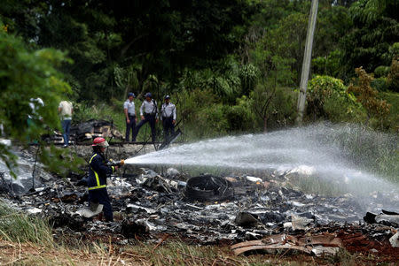 Firefighters work in the wreckage of a Boeing 737 plane that crashed in the agricultural area of Boyeros, around 20 km (12 miles) south of Havana, shortly after taking off from Havana's main airport in Cuba, May 18, 2018. REUTERS/Alexandre Meneghini