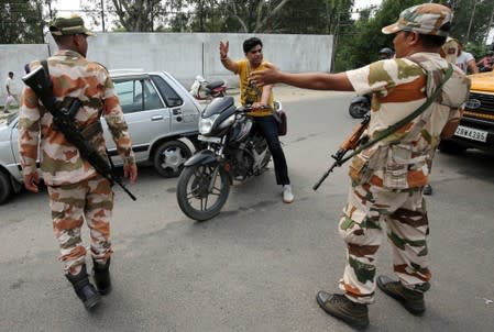 Members of Central Industrial Security Force stop a man at a check point along a road during restrictions in Jammu