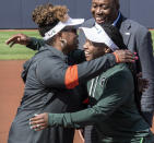 Illinois coach Tyra Perry, left, and Michigan State coach Sharonda McDonald-Kelley hug in front of Derryl Myles, Illinois assistant director of athletics, following a small ceremony before an NCAA college softball game Friday, April 21, 2023, in Urbana, Ill. The three-game series this weekend is believed to be the first time two Black female coaches have squared off in Power Five softball. (Robin Scholz/The News-Gazette via AP)