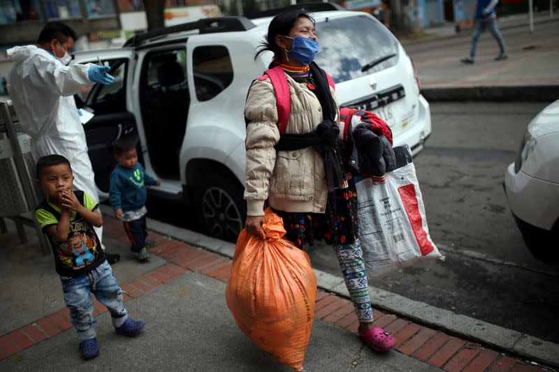 An indigenous woman wearing a protective face mask as a preventive measure against the spread of the coronavirus disease (COVID-19) carries her belongings after being evicted from a building in Bogota