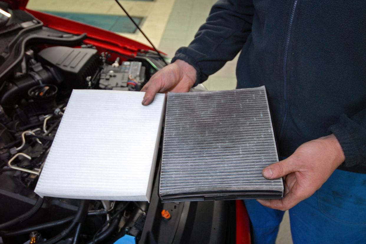 car mechanic showing clean and dirty air filters