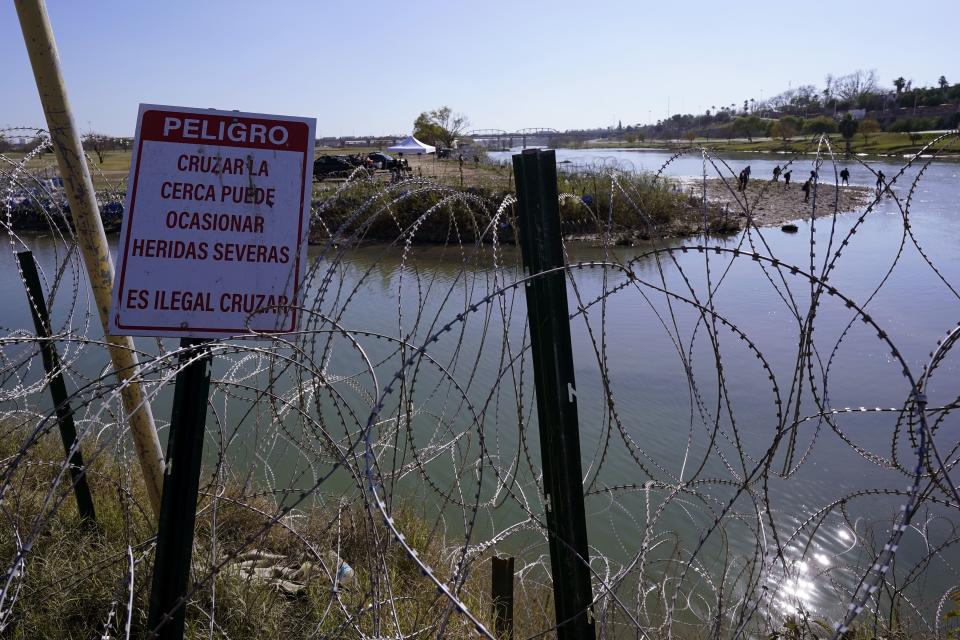 Migrants cross the Rio Grande into the U.S. from Mexico behind concertina wire and a sign warning that it’s dangerous and illegal to cross, Wednesday, Jan. 3, 2024, in Eagle Pass, Texas. According to U.S. officials, a Mexican enforcement surge has contributed to a sharp drop in illegal entries to the U.S. in recent weeks. | Eric Gay, Associated Press