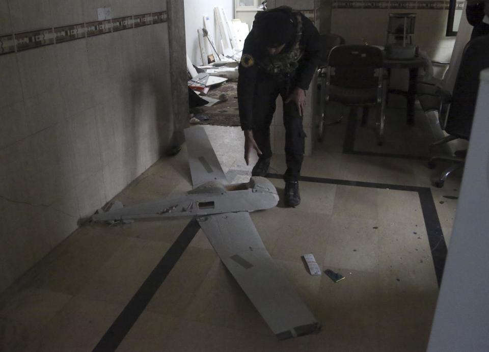 In this Saturday, Jan. 28, 2017 photo, an Iraqi officer inspects a drone belonging to Islamic State militants in Mosul, Iraq. Islamic State is hacking store-bought drone technology, using rigorous testing and tactics that mimic those used by U.S. unmanned aircraft to adapt to diminishing numbers of fighters and a battlefield that is increasingly difficult to navigate on the ground. (AP Photo/ Khalid Mohammed)