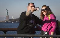 People take a photo as they line up for a harbor tour that goes past the Statue of Liberty but does not stop at the island in New York, October 12, 2013. The statue will open for tours on Sunday after the state governor of New York approved state funds for the reopening despite an ongoing government shutdown. (REUTERS/Carlo Allegri)