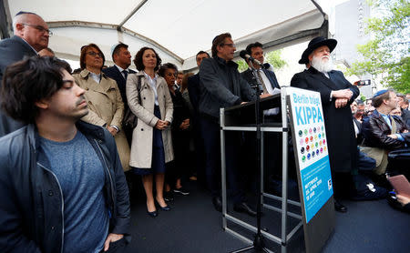 VIP and members of the Jewish Community stand on the stage during a demonstration in front of a Jewish synagogue, to denounce an anti-Semitic attack on a young man wearing a kippa in the capital earlier this month, in Berlin, Germany, April 25, 2018. The sign reads: "Berlin wears kippa." REUTERS/Fabrizio Bensch