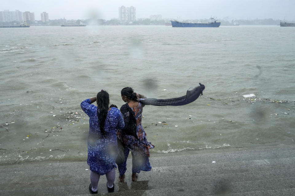 Onlookers watch a raging Hooghly River with high wind in Kolkata, India, as rain continues after cyclone Remal made a landfall near Bangladesh-India border, Monday, May 27, 2024. (AP Photo/Bikas Das)