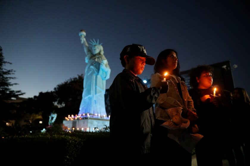 EL MONTE, CA - JUNE 18: Carmen Estrada, center, of El Monte, with twin sons Sonnie (cq) Estrada, 11, left, and Dominic Estrada, 11, attend a candlelight vigil for Cpl. Michael Domingo Paredes, 42, and Officer Joseph Anthony Santana, 31, who were killed at a motel Tuesday, is held at the Civic Center on Saturday, June 18, 2022 in El Monte, CA. The officers were were shot and killed at a motel where they were responding to a stabbing report. (Gary Coronado / Los Angeles Times)