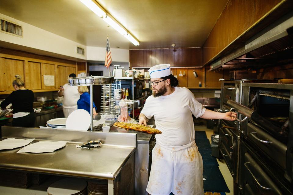 Loading a pie into the deck oven at Vito & Nick’s.