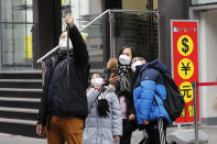 People wearing masks take photos at a shopping district in Seoul, South Korea, Tuesday, Jan. 28, 2020. Panic and pollution drive the market for protective face masks, so business is booming in Asia, where fear of the coronavirus from China is straining supplies and helping make mask-wearing the new normal. (AP Photo/Ahn Young-joon)