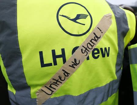 A tape reading 'United We Stand' is attached to the vest of a Lufthansa employee and member of the cabin crew union (UFO) during a protest during strike action at Frankfurt airport, Germany, November 13, 2015. REUTERS/Ralph Orlowski