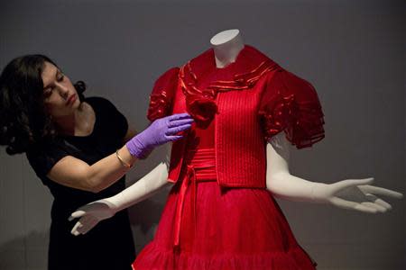 A gallery assistant poses with a red tulle evening dress by Valentino couture, 1977, during a media preview of "The Glamour of Italian Fashion 1945-2014" exhibition, at the Victoria and Albert Museum in London April 2, 2014. REUTERS/Neil Hall