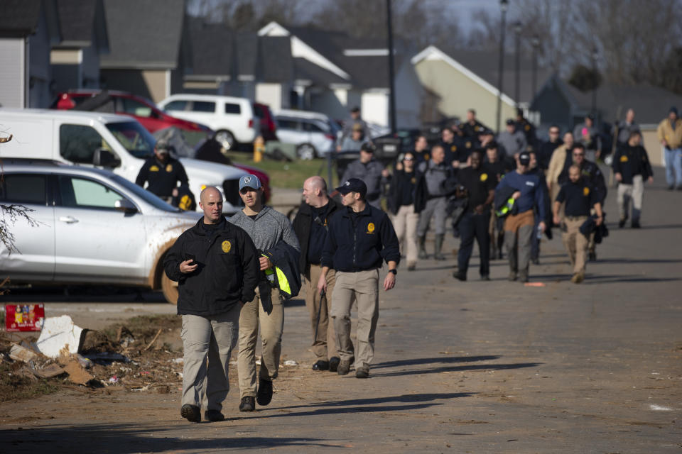 Members of police and rescue units walk along Moss Creek Avenue Tuesday, Dec. 14, 2021, in Bowling Green, Ky. When a tornado touched down in Bowling Green, fourteen people died in a few blocks, 11 of them on Moss Creek Avenue. (AP Photo/James Kenney)