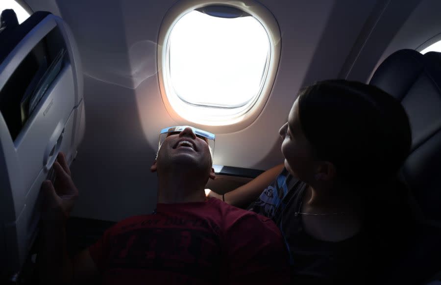 Jose Noble lays on his daughter Alayna’s lap to try and catch a glimpse of a solar eclipse as the plane passes through the path of totality during a Southwest flight 1252 from Dallas, Texas to Pittsburgh, Pennsylvania on April 08, 2024 in flight to Pittsburgh, Pennsylvania. Millions of people have flocked to areas across North America that are in the “path of totality” in order to experience a total solar eclipse. During the event, the moon will pass in between the sun and the Earth, appearing to block the sun. (Photo by Justin Sullivan/Getty Images)