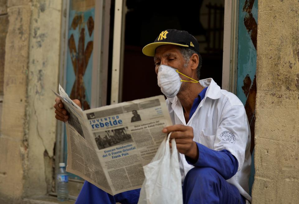 A man reads a newspaper as he wears a face mask in Havana, on March 12, 2020 as the world battles the outbreak of the new coronavirus, COVID-19. - Cuba registered its first three cases on Wednesday. Three Italian tourists, who had arrived Monday in Havana, all tested positive for the virus and have been quarantined. (Photo by Yamil LAGE / AFP) (Photo by YAMIL LAGE/AFP via Getty Images)